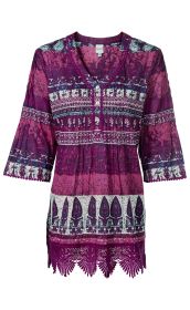 Baumwoll-Tunika in Violett mit halblangen Ärmeln, orientalischem Muster in Blau, Weiß und Violett, Knopfleiste vorne, geraffter Taillenbereich und Spitzenabschluss am Saum und Ärmeln.