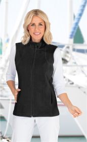 Frau trägt schwarze Baumwoll-Fleece-Weste mit Stehkragen und Reißverschluss, darüber weißes Langarmshirt, weiße Hose, Hintergrund unscharf mit maritimen Elementen wie Segelbooten und Wasser