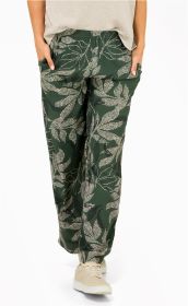 Damen trägt grüne Viskose-Hose mit weißem floralem Muster, elastischem Bund, seitlichen Händen in Taschen, kombiniert mit beigen Sneakern und hellem Oberteil, Vorderansicht, weißer Hintergrund.