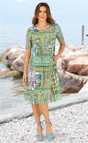 Frau trägt bunt gemustertes Viskose-Kleid mit kurzen Ärmeln, Stehkragen, knieumspielend, kombiniert mit blauen Espadrilles, steht auf steiniger Küste vor Wasser und Felsen, sommerliche Atmosphäre
