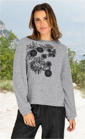 Frau trägt graues Viskose-Mix-Shirt mit schwarzem Blumendesign, lange Ärmel, steht vor Landschaft mit Bäumen und Bergen, lächelt leicht, trägt schwarze Hose