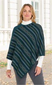 Frau trägt Baumwoll-Mix-Poncho in Blau mit diagonalen Mustern in Oliv, Schwarz und Grau, kombiniert mit weißem Rollkragenpullover und grauer Hose, steht vor weißem Gebäude mit Fenstern und Säulen, Herbstlaub auf dem Boden