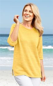 Frau am Strand trägt gelben Baumwoll-Pullover mit 3/4-Ärmeln und weißen Hosen, lächelnd, blonder langer Haar, blauer Himmel und Meereswellen im Hintergrund