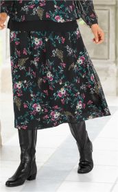 Schwarzer Viskose-Rock mit buntem Blumenmuster, knieumspielend, kombiniert mit schwarzer Transparenzbluse und schwarzen Lederstiefeln.