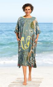 Frau am Strand trägt einen locker sitzenden Viskose-Kaftan mit abstraktem, buntem Gesichtsprint in Blau, Gelb, Rot und Beige, kurze Ärmel, Knielänge, Hände in den seitlichen Taschen, barfuß, Meer im Hintergrund