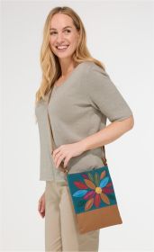 Frau trägt beige Schultertasche mit buntem Blumenmuster aus Leder und Stoff, hellgrauer Pullover mit halblangen Ärmeln, beigefarbene Hose, lächelt, weißer Hintergrund