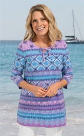 Frau am Strand trägt bunt gemustertes Baumwoll-Shirt in Blau- und Lilatönen mit Rundhalsausschnitt und Kordel, 3/4-Arm, lächelnd, vor Meer und Segelboot im Hintergrund