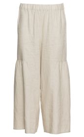 Beige Leinen-Hosenrock mit weitem Bein, elastischem Bund und Nahtdetails knapp über dem Knie, locker fallend, leichte Struktur des Stoffes sichtbar, ohne Muster, schlicht und sommerlich designed