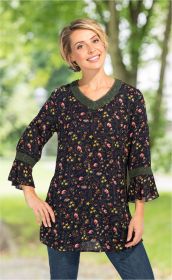 Frau trägt dunkelblaue Viskose-Bluse mit floralem Muster in Gelb, Rosa und Braun, V-Ausschnitt und drei Viertel Ärmeln mit grüner Spitzenborte, steht vor unscharfem Park-Hintergrund, lächelt leicht, hat kurze blonde Haare