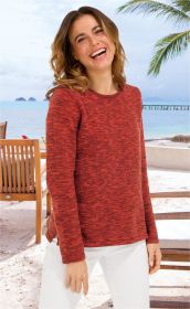 Frau lacht, trägt roten melierten Baumwoll-Pullover mit Rundhalsausschnitt und weiße Hose, steht am Strand bei Holzstühlen, Meer und Palmen im Hintergrund, sonniger Tag, entspannte Atmosphäre