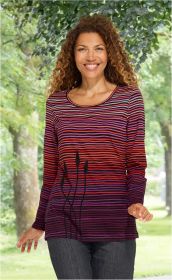 Frau mit lockigen Haaren trägt langärmeliges Baumwoll-Shirt mit horizontalen Streifen in Rot, Lila und Schwarz, dazu schwarzes Pflanzenmuster, im grünen Park stehend, lächelnd