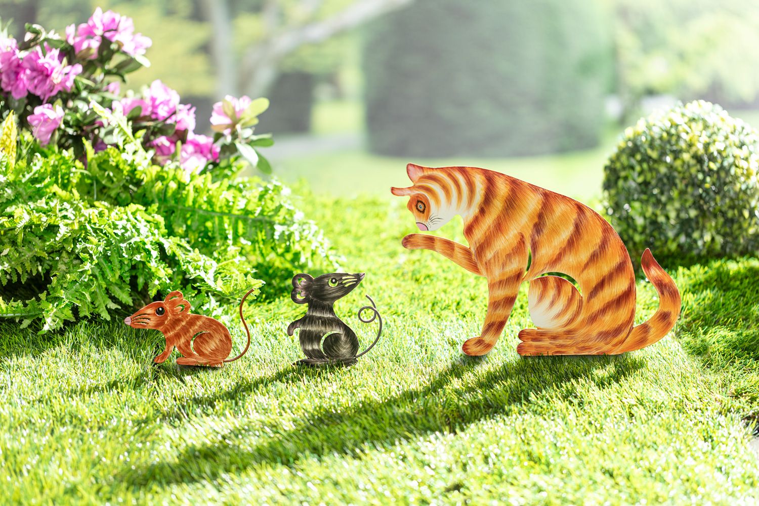 Metall-Gartenstecker Set bestehend aus einer orangetigergestreiften Katze und zwei Mäusen in Braun und Schwarz auf grünem Rasen mit Blüten und grünen Büschen im Hintergrund