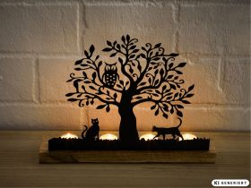 Teelichthalter aus Holz und schwarzem Metall mit Baum, Eule auf Ast und zwei Katzen, drei brennende Teelichter beleuchten die Silhouetten, Hintergrund weiße Mauer, warme Lichtstimmung