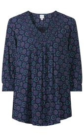 Viskose-Bluse mit dreiviertel langen Ärmeln, dunkelblauem Stoff mit buntem Kreismuster in Blau und Violett, V-Ausschnitt mit dekorativer Rüscheneinfassung und leichtem Faltenwurf unterhalb des Kragens.