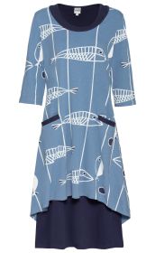 Baumwoll-Kleid in Blau mit weißem Fischmuster, dreiviertel Ärmeln, Rundhalsausschnitt und asymmetrischem Saum, vorne zwei Eingrifftaschen mit dunklem Besatz, darunter dunkelblauer Unterrock sichtbar.
