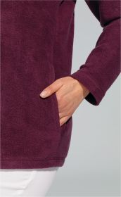 Hand in Tasche einer dunkelvioletten Baumwoll-Fleece-Jacke mit sichtbarer weicher Struktur, Ärmel mit Saum, getragen zu weißer Hose, vor hellem Hintergrund