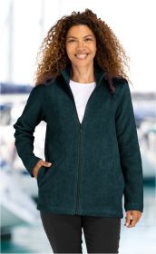 Frau mit lockigem Haar trägt eine dunkelgrüne Baumwoll-Fleece-Jacke mit Reißverschluss und Stehkragen, eine Hand in der Tasche, vor unscharfem Hafenhintergrund.