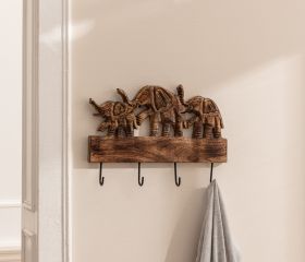 Holzgarderobe mit vier Haken, verziert mit drei geschnitzten Elefantenfiguren, an einer hellen Wand montiert, ein graues Kleidungsstück hängt an einem Haken