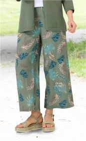Grüne Viskose-Hose mit weiten Beinen und buntem Blattmuster in Blau und Beige, kombiniert mit grünem Cardigan, weißen Sandalen mit geflochtenem Plateau-Sohlen-Design, Outdoor-Hintergrund mit Rasen und Weg