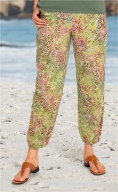 Viskose-Hose mit lockerem Schnitt und elastischem Saum, hellgrün mit buntem, floralen Blattmuster, getragen am Strand, kombiniert mit braunen offenen Sandalen, Hintergrund Meer und Sandstrand.