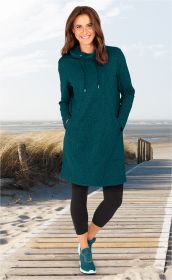 Frau am Strand auf Holzsteg trägt jagdgrünes Viskose-Mix-Kleid mit Tunnelzugkragen und Eingrifftaschen, schwarze Capri-Leggings und passende Sneaker.