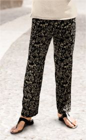 Beinansicht einer Person, die eine schwarze Viskose-Hose mit beigem floralem Muster trägt, kombiniert mit schwarzen Sandalen und einem beigefarbenen Oberteil, stehend auf hellem gepflastertem Boden