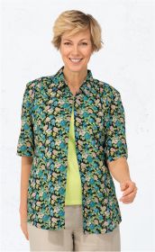 Frau trägt kurzärmelige Viskose-Mix-Bluse mit blau-beigem Blumenmuster auf schwarzem Grund, offenes Design über hellgrünem Top, kombiniert mit hellbeiger Hose, heller Hintergrund, lächelnd, kurze blonde Haare