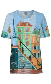 Baumwoll-Shirt mit Rundhalsausschnitt in hellblau, bedruckt mit bunten Häusern, Treppen, schwarzen Katzen, Fahrrad mit Blumenkorb und angedeutetem Eiffelturm, alles vor gestreiftem Hintergrund in Blau, Grün und Braun.