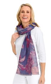 Frau trägt weißen Pullover und hellblaue Hose, lächelnd mit langem, leichter Baumwoll-Leinen Schal in Blau mit großem floralem Muster in Pink- und Lilatönen um den Hals geschlungen.