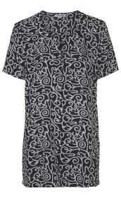 Schwarze Viskose-Tunika mit kurzem Arm, rundem Ausschnitt und Knopfleiste, weißes abstraktes Ornamentmuster über die gesamte Tunika verteilt, gerade geschnitten, leichte Stoffqualität.
