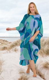 Frau läuft barfuß am Strand, trägt bunten Viskose-Kaftan mit abstraktem Patchwork-Muster in Blau-, Grün- und Türkistönen, lächelt freundlich, Sand und Dünen im Hintergrund, heller Himmel.