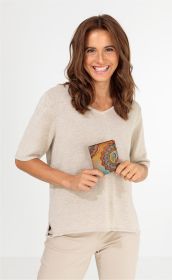Frau mit braunen Haaren lächelt und hält eine braune Geldbörse mit buntem Mandala-Muster vor beigem Pullover und hellen Hosen vor weißem Hintergrund