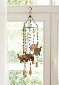 Metall-Mobile 60cm mit drei goldfarbenen Elefanten, bunten Glasperlen und kleinen Glocken, hängend vor einem Fenster mit weißem Vorhang und grünem Hintergrund draußen