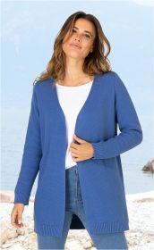 Frau trägt offene blaue Baumwoll-Strickjacke mit gerippten Bündchen, weiße Bluse und blaue Jeans, steht am Kiesstrand vor See und bewölktem Himmel