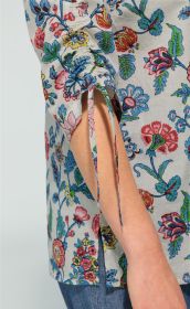 Detailaufnahme des Ärmels einer Baumwoll-Bluse mit floralem Muster in Blau, Rot und Pink, gerafftem Bereich und Schlitz mit Bindebändern, getragen zu blauer Jeans.