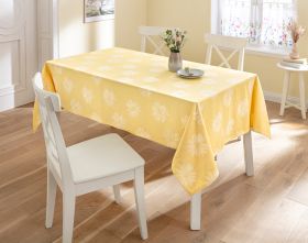 Gelbe Baumwoll-Tischdecke DM180 mit weißem Blumenmuster auf weißem Esstisch, umgeben von weißen Stühlen, geschmückt mit Vase und Blumen, helles Esszimmer mit Holzfußboden und Fenster mit floralem Vorhang