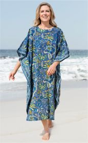 Frau am Strand trägt blauen Baumwoll-Kaftan mit gelb-grün-blauem Blumenmuster, leichte weite Passform, halblange Ärmel, barfuß auf Sand vor ruhigem Meer und blauem Himmel.