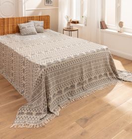 Baumwoll-Überwurf 250x240 mit grauem Elefanten- und Blättermuster, weiße Fransen am Rand, dekoriert mit zwei passenden Kissen, liegt auf Bett mit Korbgeflecht-Kopfteil, helles Schlafzimmer mit Holzfußboden und großem Fenster