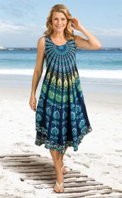 Frau am Strand trägt ärmelloses, knielanges Viskose-Kleid mit blau-grün-gelbem Mandala-Muster, lächelnd, blonde gewellte Haare, weiße Sandalen, blauer Himmel und Meer im Hintergrund