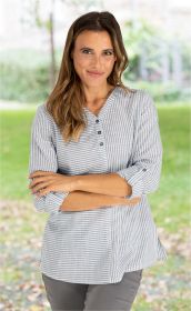 Frau trägt graue, gestreifte Baumwoll-Bluse mit Knopfleiste und hochgekrempelten Ärmeln, vor unscharfem Gartenhintergrund, Arme verschränkt, leichte Frontalaufnahme, natürliche Frisur und dezentes Make-up