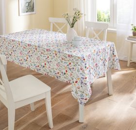 Baumwoll-Tischdecke 160cm mit buntem Blumenmuster auf rechteckigem Esstisch, umgeben von weißen Stühlen, weißer Vase mit Blumen in hellem, sonnigem Esszimmer mit Holzfußboden und großem Fenster.