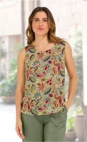 Frau trägt ärmelloses Modal-Top mit buntem floralen Muster in Rot, Blau, Grün und Gelb, dazu grüne, locker sitzende Hose, Hände in Taschen, unscharfer urbaner Hintergrund.