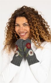 Frau mit lockigem braunem Haar lächelt, trägt graue Alpaka-Pulswärmer mit roten und weißen Blumenmotiven, weiße langärmlige Kleidung, Hände vor dem Gesicht gehalten.
