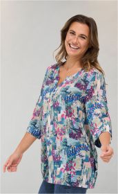 Frau trägt bunte Modal-Tunika mit abstraktem Muster in Blau-, Pink- und Grüntönen, 3/4-Ärmel, V-Ausschnitt mit Knopfleiste, lächelnd, seitliche Taschen, hellgrauer Hintergrund
